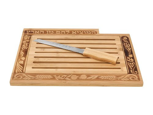 קרש חלה מעץ עם חריצים, עיטורי צמחים וכתובת, כולל סכין תואמת המונחת עליו במבט מלמעלה.