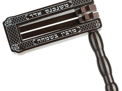 רעשן עץ ענק בעיצוב מלבני עם ידית אחיזה מעוגלת, ועליו הדפס עיטורים וכיתוב משנכנס אדר מרבין בשמחה במראה אלכסוני.
