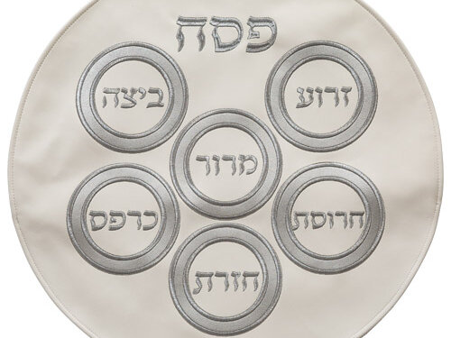 כיסוי מצה עגול מדمוי עור עם רקמה הכוללת את המילה פסח ועיجולי סימני הסדר במבט מלמעלה.