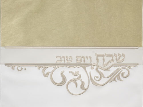 כיסוי חלה מעוצב מדמוי עור בעיצוב אופקי, עם רקמה בולטות של הכיתוב שבת ויום טוב ועיטורי תחרה בתחתית, צילום מלמעלה.