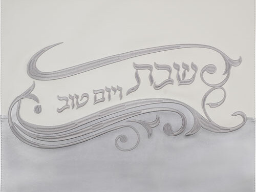 כיסוי חלה מדُمוי עור בעיצוב אלגנטי הכולל עיטורים מובלטים והכיתוב שבת ויום טוב במרכז, במבט חזיתי מלמעלה.