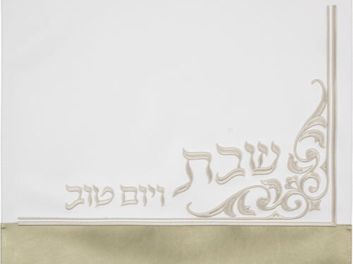 כיסוי חלה דמוי עור במבט מלמעלה, עם עיטור אורنמנטלי בפינה הימנית והכיתוב שבת ויום טוב בחלק התחתון מעל פס רחב