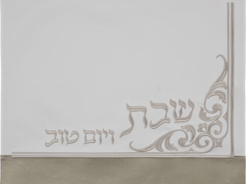 כיסוי חלה דמוי עור במבט מלמעלה, עם עיטור רקמה פינתי הכולל את הכיתוב שבת ויום טוב ופס תחתון רוחבי.