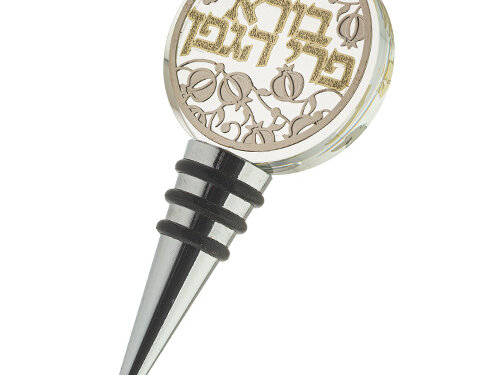 פקק בקבוק יין מקريסטל עם ראש עגול, פלקטה מעוטרת ברימונים וכיתוב בורא פרי הגפן, ופקק מחודד עם טבעות אטימה נשלפות.